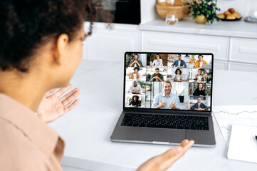 African american successful young woman talking on video conference with multiracial business team, discussing the project and strategy. Online meeting, brainstorm of employees, online conversation