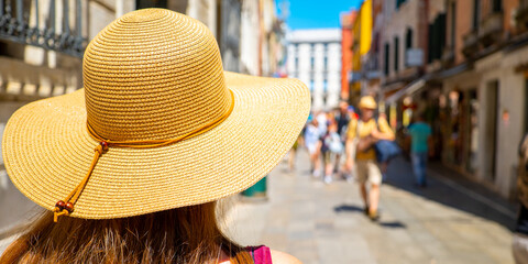 A woman with a hat walking in Venice on a sunny summer and holiday day.