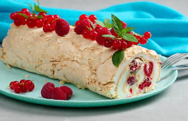 Baked meringue roll with red berries on a round plate, white background