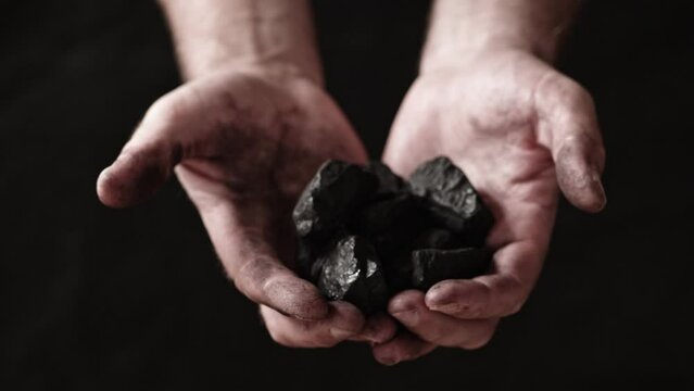 A miner shows the pieces and nuggets of coal in his hands.