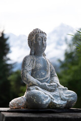 Stone statue of a Buddha praying in front of a mountain landscape