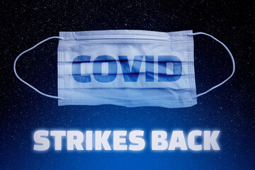 The return of the coronavirus. Lettering Covid Strikes Back and medical mask. A new jump in the...