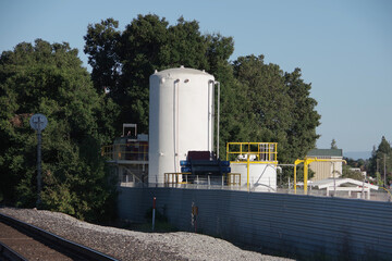 Obraz premium Landscape with trees and an industrial silo next to train tracks