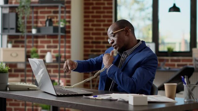 Male Secretary Answering Landline Phone Call At Startup Job, Having Remote Conversation With Business Leader. Chatting On Office Telephone To Talk To Boss On Phone Line, Telework. Tripod Shot.