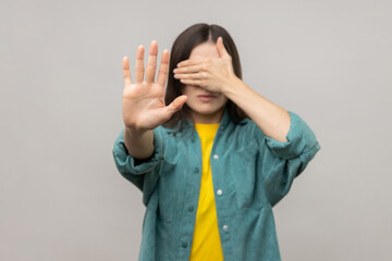 I don't want to watch. Portrait of scared confused adult woman covering eyes, showing stop gesture,...