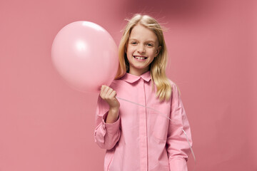 Obraz na płótnie Canvas horizontal portrait of a cute beautiful, happy girl with a pink balloon in a pink dress on a pink background with an empty space for an advertising tex