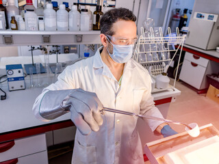 Scientist removing a sample from the furnace. Selective focus.