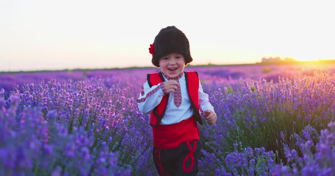 Happy bulgarian boy in traditional folklore costume running in lavender field