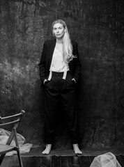portrait of a girl on a dark gray background.a young beautiful Ukrainian girl posing on a dark gray background with different emotions. blonde with long hair in a black suit isolated.