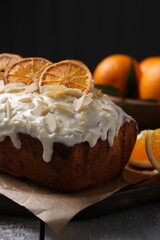 Delicious sweet cake with dry orange and almond petals on grey wooden table