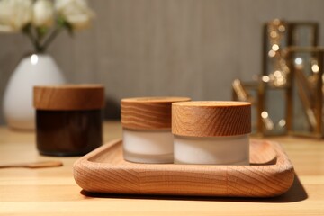 Jars of cream and tray on wooden table
