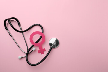 Female gender sign and stethoscope on pink background, flat lay. Space for text