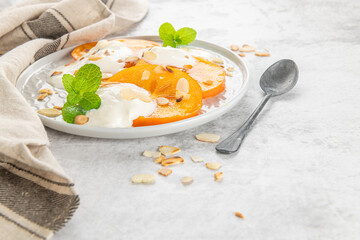 Sliced persimmon with yogurt and almonds. Healthy food concept on light background. top view