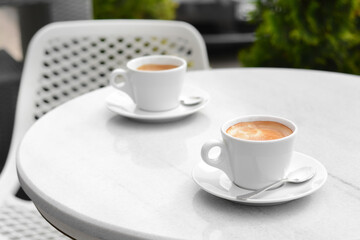 Ceramic cups of aromatic coffee with foam on table in morning