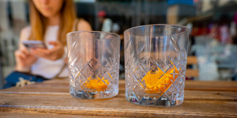 Empty glasses with a slice of orange stand on the table on a hot sunny day.
