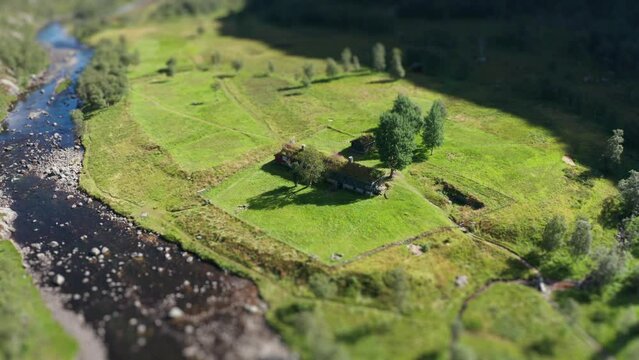 An aerial view of a traditional sod roof cabin on the river bank. Tilt-shift video. Slow-motion, orbit.