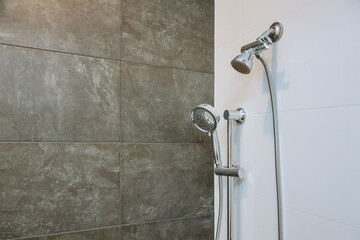 There is an elegant stainless steel shower head in the bathroom, of the wall with the new shower head