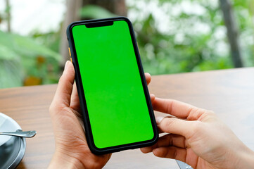 Mockup image of a business people holding smart mobile phone with blank green screen on vintage...