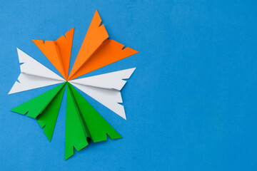 Indian tricolor paper planes arranged in circular shape on blue background. Conceptual image for...