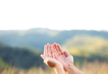 Hands together and open symbolizing the concept of receiving, with landscape with mountains in the background. Receiving God's Blessing.