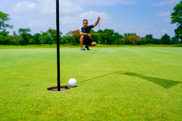 Obraz premium Golfer putt golf ball into hole on the green at golf course