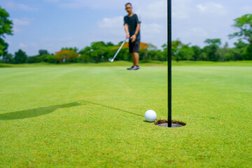 Obraz premium Golfer putt golf ball into hole on the green at golf course