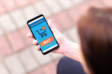 Woman shopping online on her smartphone. Mobile display showing an online shopping cart with checkout button