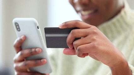 Woman shopping online using her credit card and phone, using a banking app for secure payment for her internet order. Closeup of happy black female shopper at home buying and paying bills on web