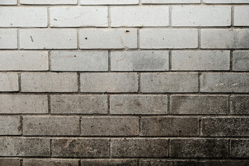 Weathered brick wall made from white bricks with white mortar, showing surface wear, scuffs and discoloration