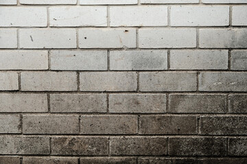 Weathered brick wall made from white bricks with white mortar, showing surface wear, scuffs and...