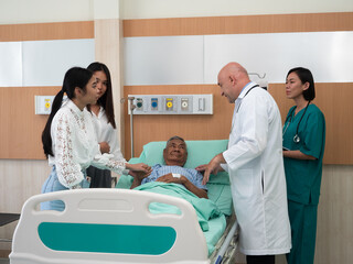 In hospital treatment room relative visit patient holding hand and doctor explain his illness condition and cheerful
