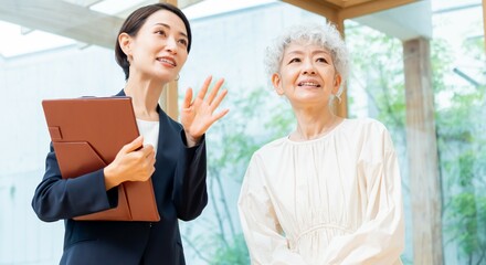 家を案内するスーツを着た日本人女性とシニア女性