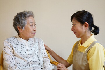仲良く向かい合う高齢女性と中年女性　カメラ目線　介護イメージ