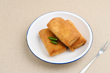 Risoles Rogout, Indonesian traditional savory snack. Filled with chicken chopped and mix vegetable, covered with bread crumb and deep fried. Served in white plate with chilli.