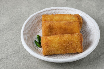 Risoles Rogout, Indonesian traditional savory snack. Filled with chicken chopped and mix vegetable, covered with bread crumb and deep fried. Served in white plate with chilli.