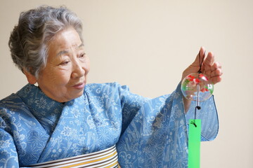 着物(高級浴衣の絹紅梅)を着て風鈴を持つ高齢女性