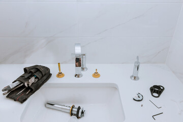 As part of his work, the plumber assembles, installs, and adjusts water faucet in the bathroom