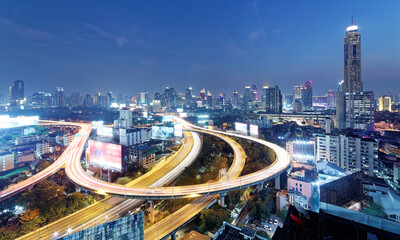 Night scenery of Bangkok with skyscrapers in background and busy traffic trails on elevated...