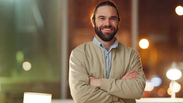 Portrait of proud man standing with arms crossed and looking confident in his office at night. Face of happy IT technician specialist smiling while working late to assist with business