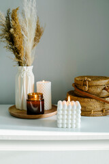 Home interior floral decor. Dried flowers in vase on white shelf and wooden tray with various...