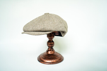 Detail of a classic eight-panel newsboy hat, in khaki herringbone tweed fabric set against a bronze...