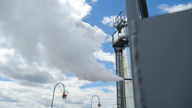 Chemical plant pipelines and water steam. Air pollution. Heavy industry. Billowing steam from smoke stack in sky. Large industrial tubing and piping inside central heating plant. Steam heat exchangers