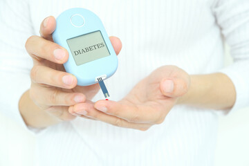 Human hand checking blood sugar with digital tear meter diabetes health check Health and medical concepts.