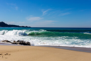 A view on Pacific ocean coast with blue sky and water and waves