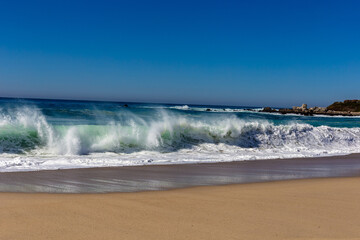 A view on Pacific ocean coast with blue sky and water and waves