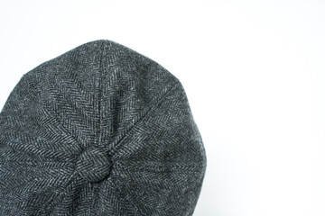 Detail of a classic eight-panel newsboy hat, in midnight dark herringbone tweed fabric set against...