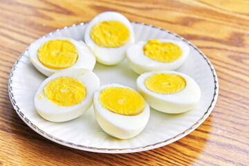 Half boiled eggs laid out in white plates and served on a wooden table.