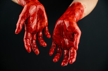 Women's hands in blood on a black background.