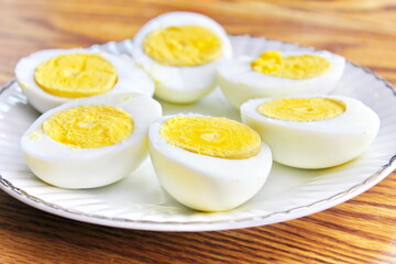 Half boiled eggs laid out in white plates and served on a wooden table.