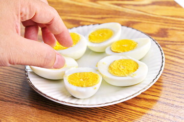 Half boiled eggs laid out in white plates and served on a wooden table.